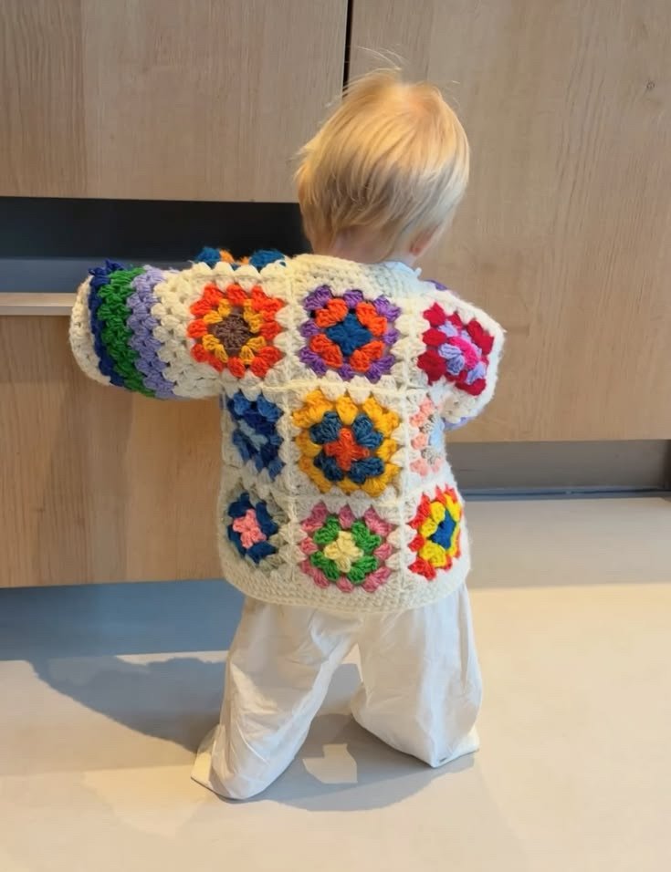 Criança com casaquinho de quadradinhos coloridos